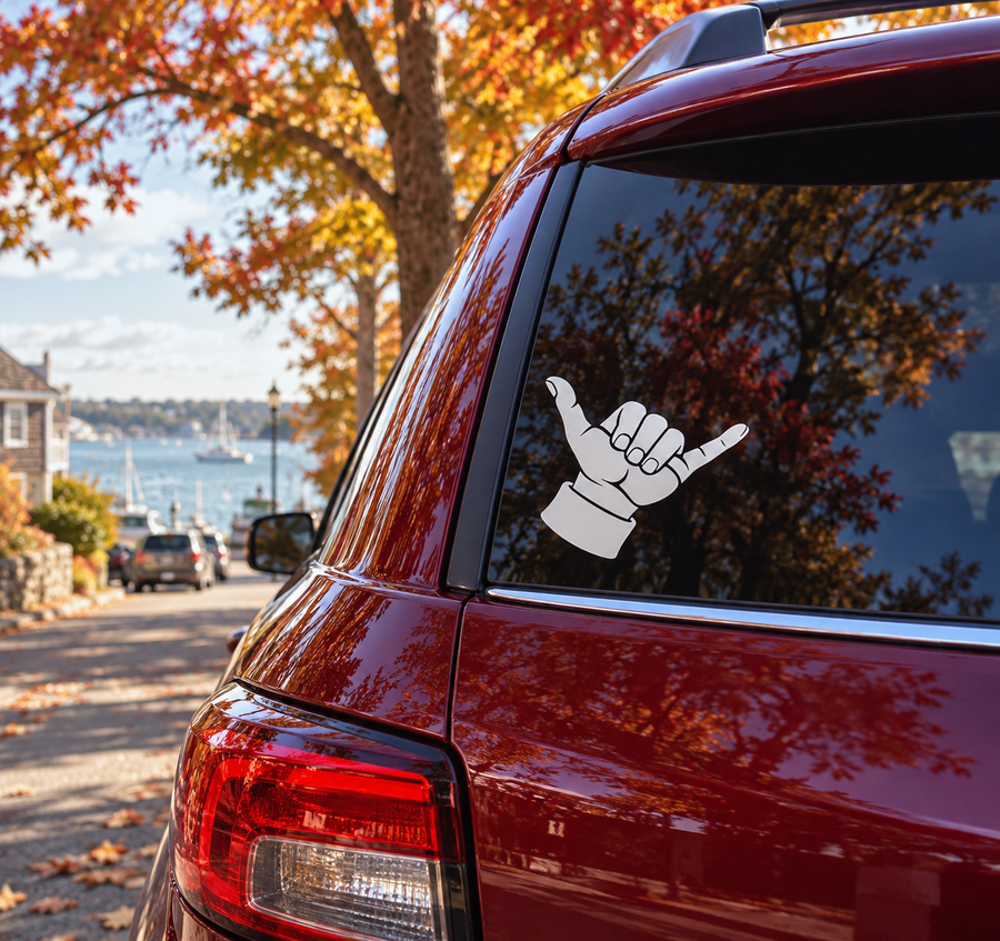 Backhand shaka vinyl decal on car rear window, white outline on dark hand gesture