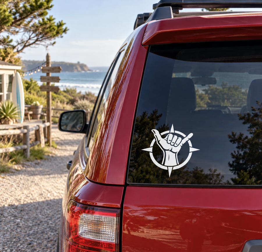 White compass-and-shaka hand vinyl decal on red car window