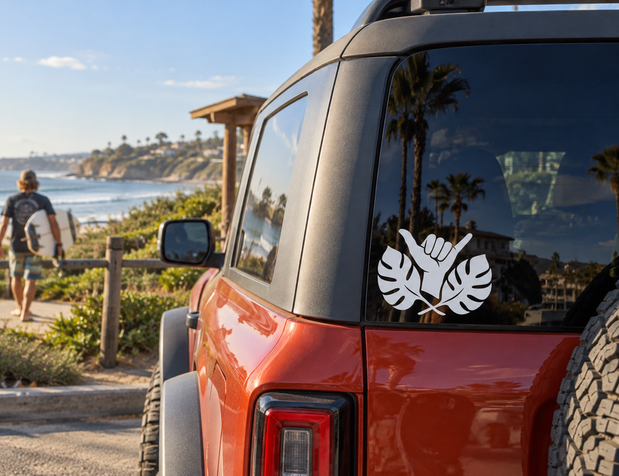 Black shaka hand vinyl decal with tropical leaf shapes on car window