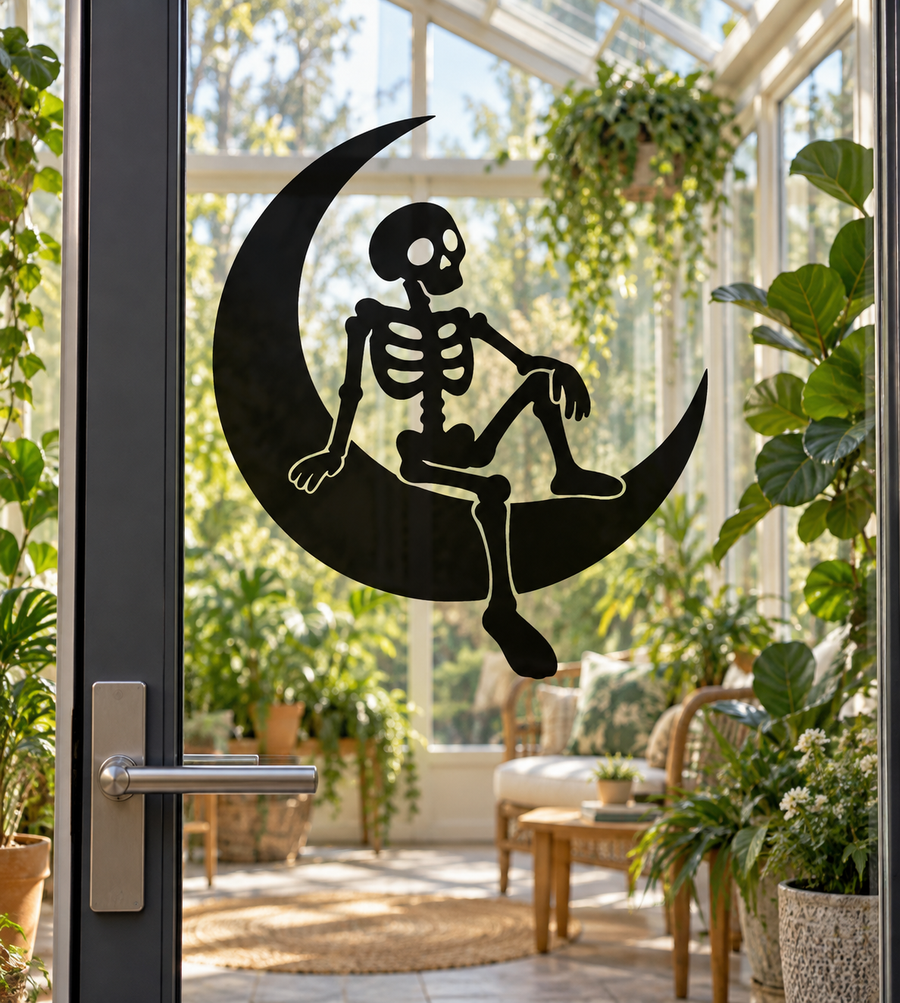 Black skeleton seated on a crescent moon vinyl decal