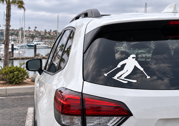 Skiing vinyl decal on car rear window, white skier silhouette with poles.
