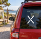 Crossed skis vinyl decal on car rear window, white skis on dark glass