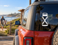 Bottle-shaped vinyl decal with bold X graphic on a vehicle window