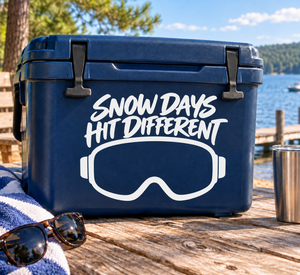 Blue cooler with white skiing goggles vinyl decal reading 'Snow Days Hit Different'