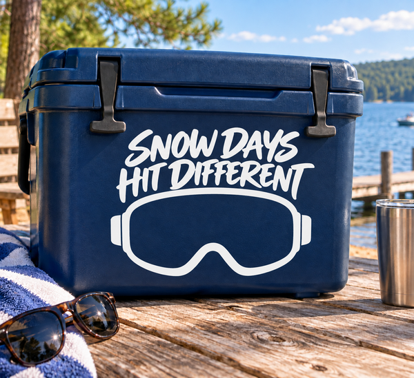 Blue cooler with white skiing goggles vinyl decal reading 'Snow Days Hit Different'