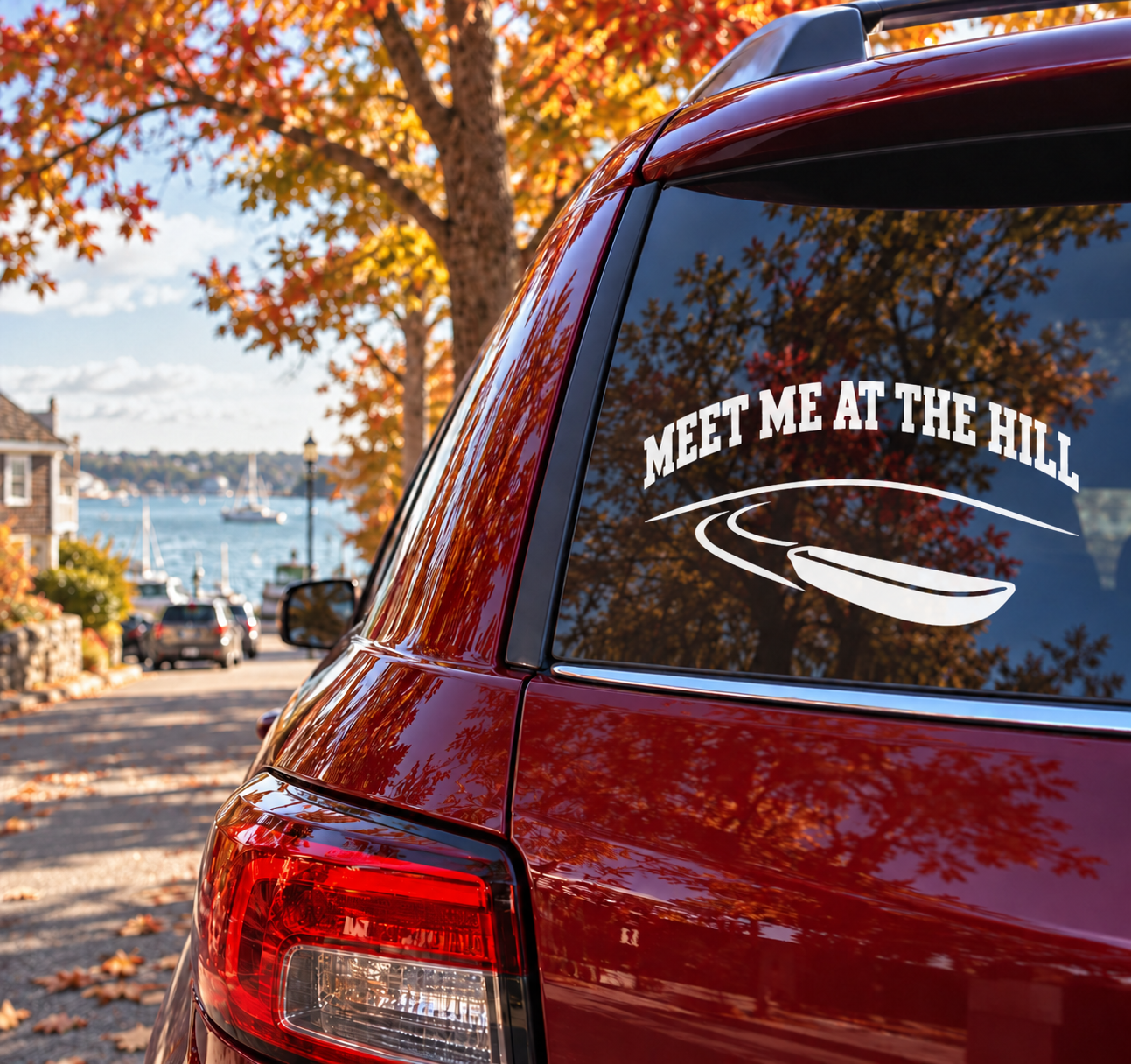 Car window vinyl decal with "MEET ME AT THE HILL" text and sled graphic