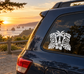 White tiki faces vinyl decal with hibiscus on dark car rear window