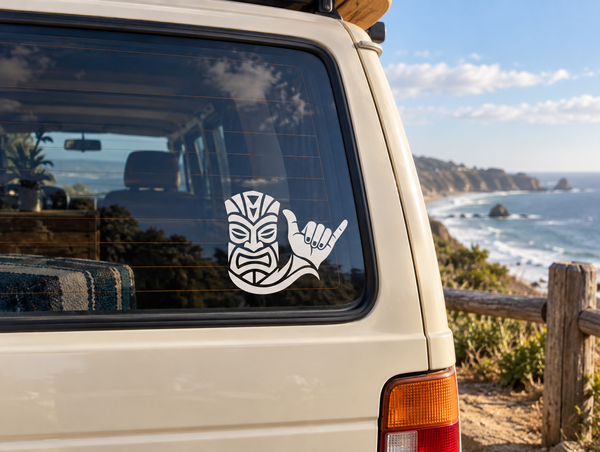 Tiki vinyl decal with tribal mask face and raised hand on a car window
