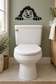 Cartoon yeti face vinyl wall decal with arms resting on a horizontal bar above toilet