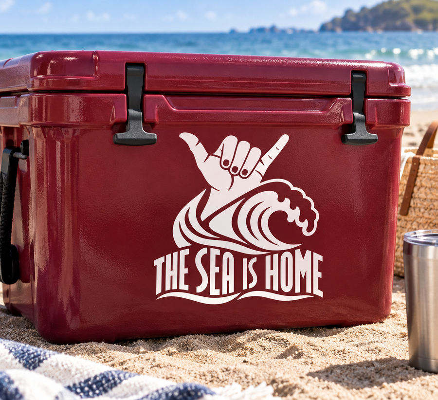 Vinyl wave decal with stylized hand, fish, and 'THE SEA IS HOME' lettering.