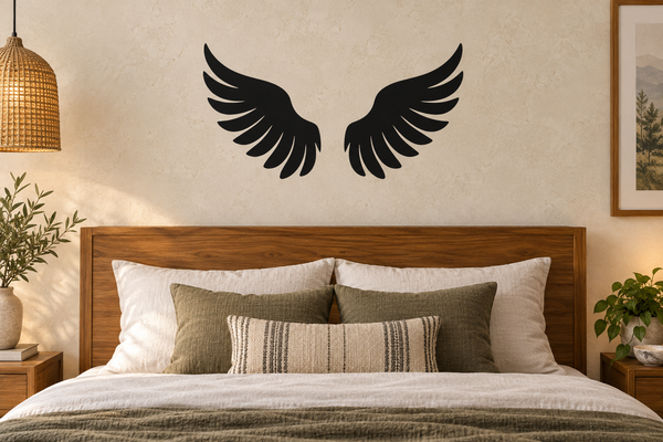 Pair of black angel wing vinyl decals on wall above a bed