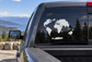 World map continents vinyl decal on car window, white continents against dark glass.