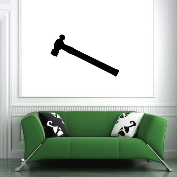 Wall hammer decal with black ball-pein silhouette above green sofa and patterned pillows