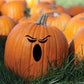 Booing face decal with black angry eyebrows and oval mouth on orange pumpkin
