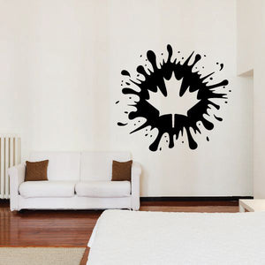 Paintball splatter decal with black leaf-like burst on a light wall