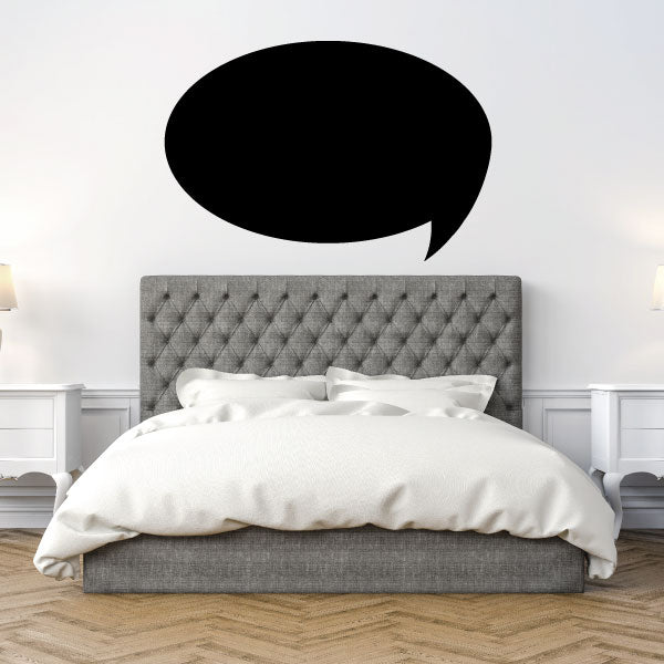 Black filled oval speech bubble decal with rounded tail above bed headboard.