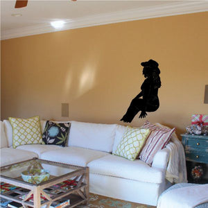 Black cowgirl silhouette wall decal with hat and boots near sofa