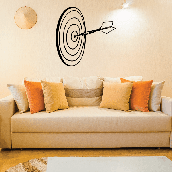 Dart hitting board wall decal with black target rings and dart, mounted above couch
