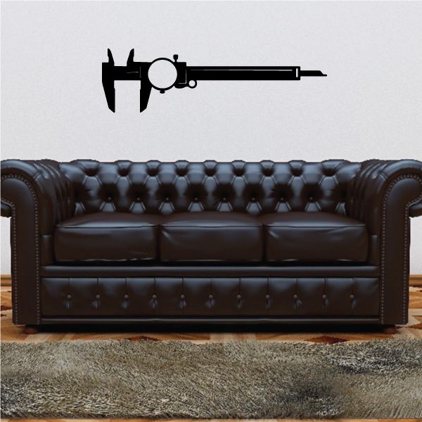 Black dial caliper vinyl decal on a light wall above a dark brown sofa