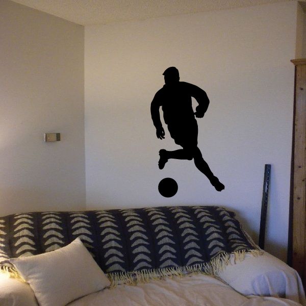 Soccer player dribbling ball wall decal, black silhouette on light surface