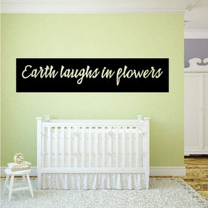 Wall decal: black banner with 'Earth laughs in flowers' text
