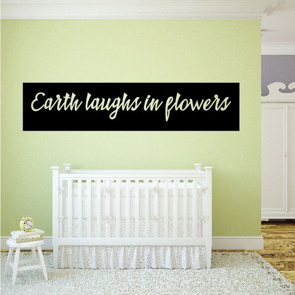 Wall decal: black banner with 'Earth laughs in flowers' text