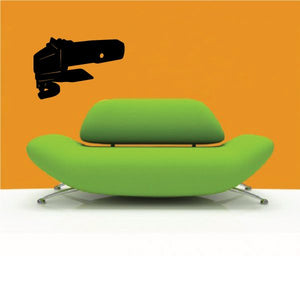 Electric shears decal with black tool above green upholstered sofa cushion