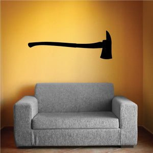 Black fire axe wall decal with axe silhouette on a wall above a sofa