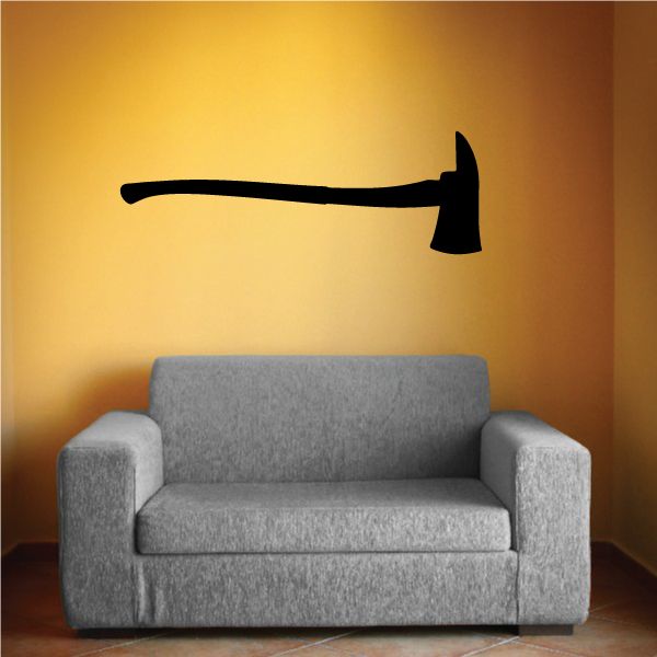 Black fire axe wall decal with axe silhouette on a wall above a sofa