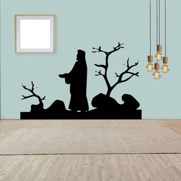 Religious wall decal with black silhouette of Jesus, rocks, and bare tree branches