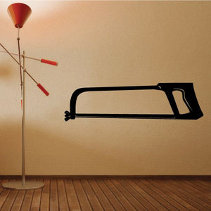 Large hack saw wall decal, black silhouette with angled handle and blade teeth.
