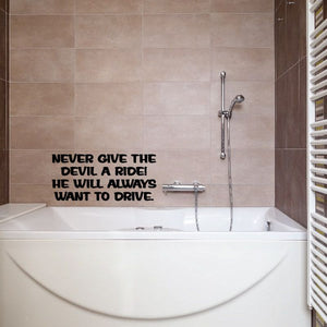 Bathroom wall decal with bold black text: NEVER GIVE THE DEVIL A RIDE! 