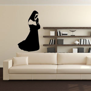 Praying nun wall silhouette decor, dark cutout figure with hood and robe