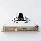 Ornate pilgrim hat wall decal with decorative scroll accents, black silhouette.
