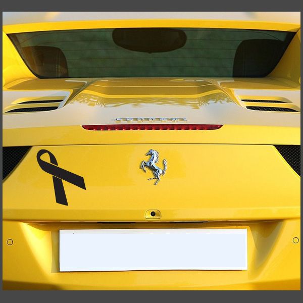 Black ribbon decal on yellow car trunk with centered prancing horse emblem