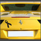 Black ribbon decal on yellow car trunk with centered prancing horse emblem
