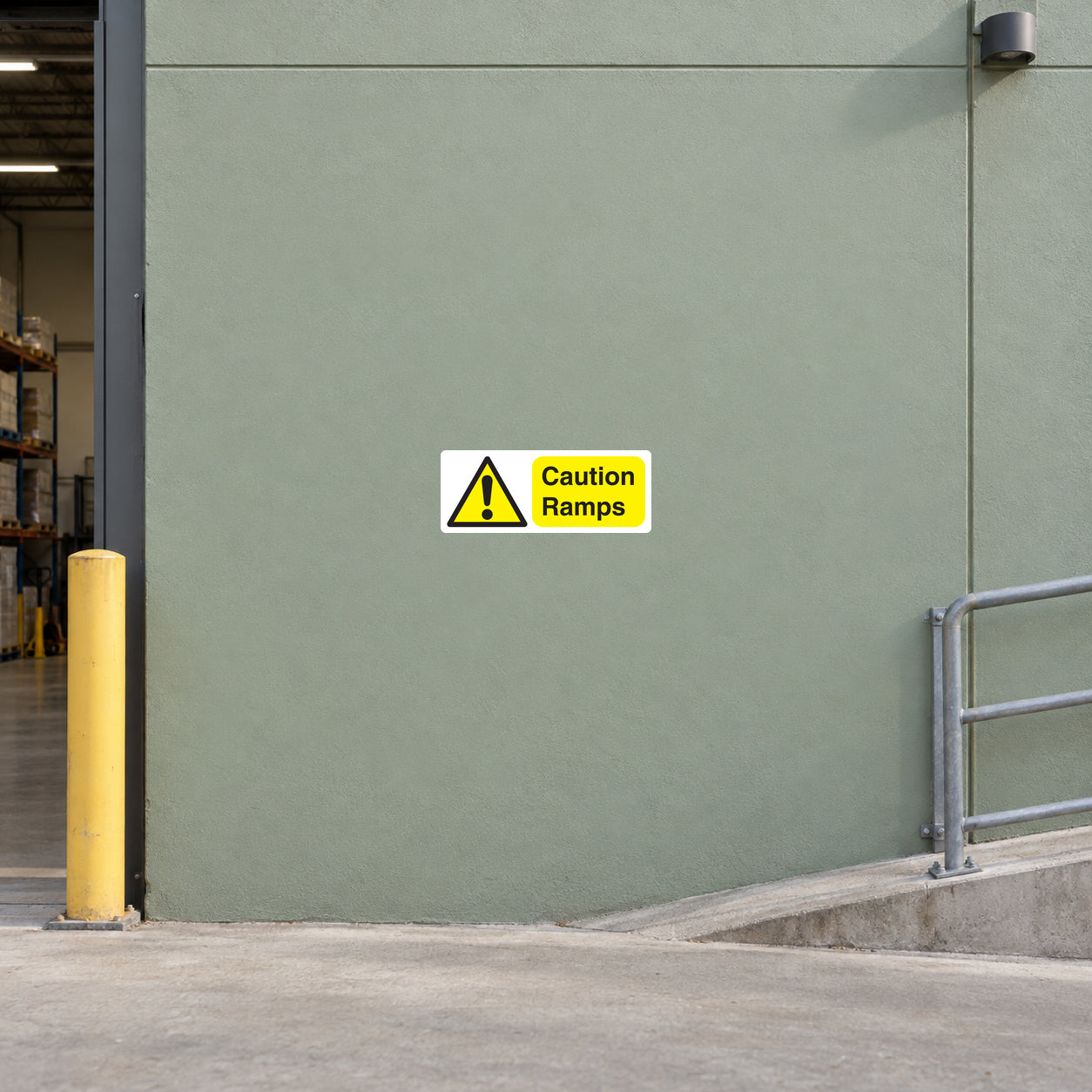 Caution Ramps Sticker applied in Broad smooth sage wall beside a short warehouse access ramp, central mounting panel faces camera, ramp slopes only along lower right edge and rail stays far right.