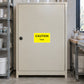 Caution Toxic Sticker applied in Closed pale beige toxic-material storage cabinet in a ceramics glaze laboratory, broad smooth single central door, lock far left and glaze preparation bench glimpse far right.