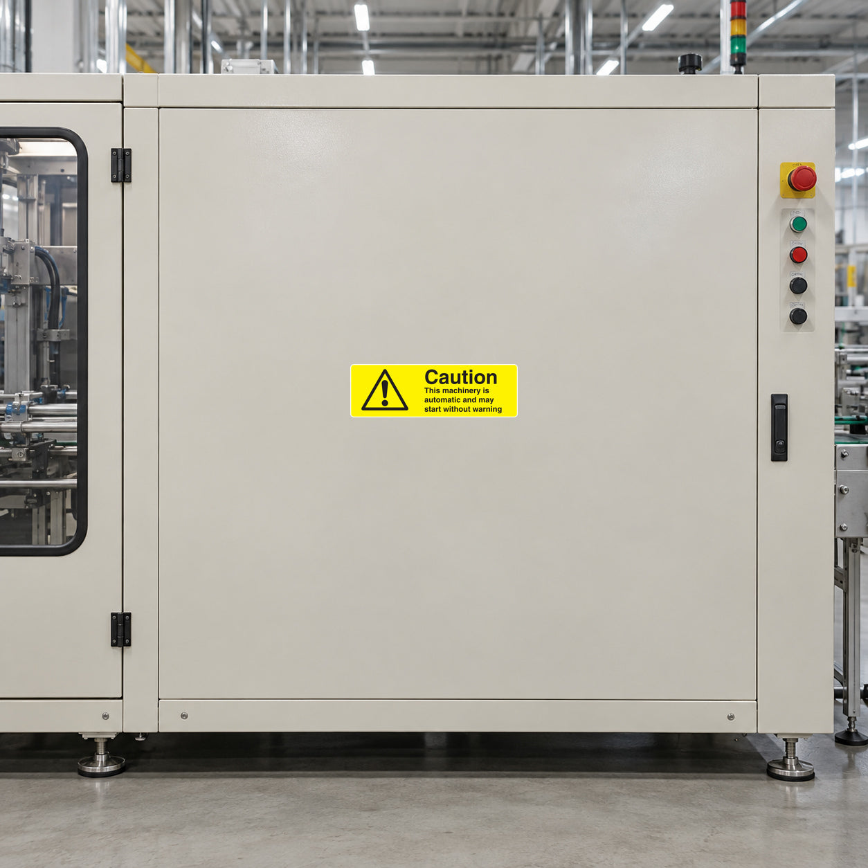 Caution The Machinery Is Automatic Sticker applied in Broad smooth ivory guarded robotic packaging machine enclosure panel in a clean manufacturing hall, central unbroken face, closed inspection window extreme left and controls extreme right.