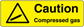 Caution compressed gas sticker with warning triangle and bold text on yellow background