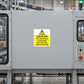 Caution machinery sticker with yellow triangle and warning text on industrial panel