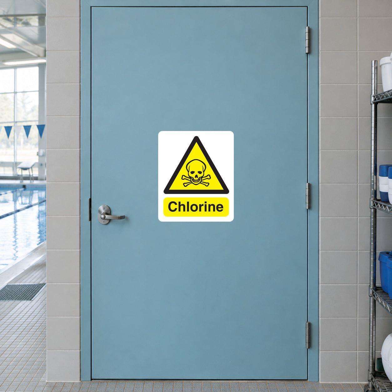Caution Chlorine Sticker applied in Closed aqua pool chemical storage room door beside an indoor swimming facility, broad unbroken opaque door surface, latch extreme left, pale ceramic tiled jamb and small hint of pool flooring at bottom.