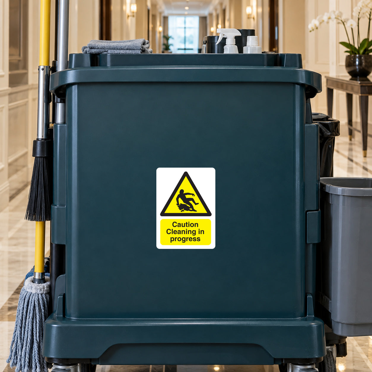 Caution Cleaning in Progress sticker on a janitorial cart in a hotel corridor