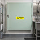 Danger Caustic Sticker applied in Closed broad pale mint caustic cleaning supply cabinet in a food manufacturing utility room, smooth central face, latch far left, stainless wash area only far right.