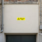 Danger Mind Your Head Sticker applied in Broad smooth flat ivory fascia above a low basement doorway at an old warehouse, central fascia clear and unobstructed across x25%-75% y15%-74%, opening visible only lower edge, pipes far sides.