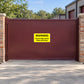 Yellow warning sticker on brown gate: WARNING—Guard dogs patrol these premises.