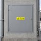 Warning Confined Space Sticker applied in A solid grey closed confined space access panel on a concrete service enclosure, pipe edges far sides