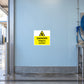 Danger slippery surface warning sticker with yellow triangle on a wall