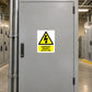 Danger Electric Shock Risk sticker on a closed industrial electrical cabinet