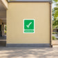 Emergency Assembly Point Sticker applied in school outdoor assembly courtyard, smooth pale yellow masonry wall, open paved gathering space and distant trees outer edges